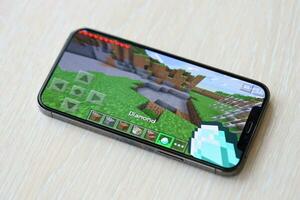 Minecraft mobile iOS game on iPhone 15 smartphone screen on wooden table during mobile gameplay photo