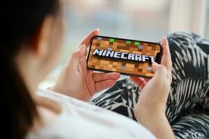 Minecraft mobile iOS game on iPhone 15 smartphone screen in female hands during mobile gameplay photo