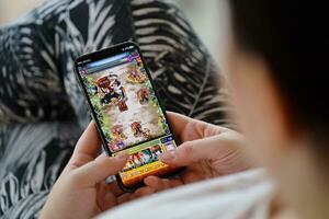 Monster Strike mobile iOS game on iPhone 15 smartphone screen in female hands during mobile gameplay photo