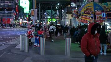 nuovo York città, Stati Uniti d'America - gennaio 23, 2021 persone indossare maschere attraversamento un' strada a volte piazza a notte durante coronavirus pandemia nel inverno giorno. macchine passaggio di. midtown Manhattan video