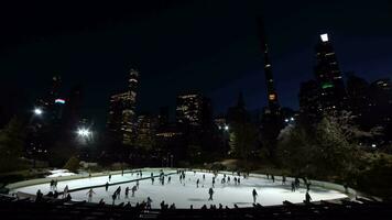 nuevo York ciudad, Estados Unidos - enero 22, 2021 personas vistiendo mascaras patinaje sobre hielo en Wollman pista en central parque en el noche durante coronavirus pandemia. centro de la ciudad paisaje urbano video