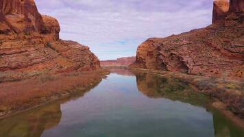 Colorado río y rojo arenisca montañas en soleado día. cielo reflexión en agua. grandioso condado, Utah, EE.UU. aéreo vista. zumbido moscas adelante y hacia arriba video