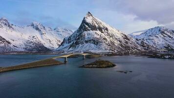 Fredvang Bridge, Car and Volandstind Mountain in Winter at Sunset. Flakstadoya, Lofoten Islands, Landscape of Norway. Aerial View. Drone Flies Forward and Upwards video