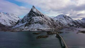 Fredvang ponte, auto e volandstind montagna nel inverno. Flakstadoya, lofoten isole, paesaggio di Norvegia. aereo Visualizza. fuco mosche indietro e verso l'alto video