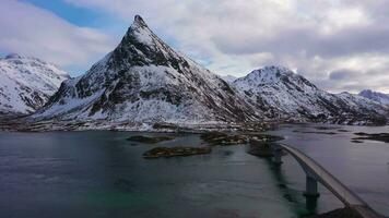 Fredvang puente y volandstind montaña en invierno. flakstadoya, lofoten islas, paisaje de Noruega. aéreo vista. zumbido moscas adelante y hacia arriba video