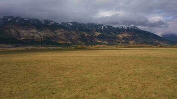 Teton Berg Angebot und rot Wiese auf Herbst wolkig Tag. Jackson Loch, Wyoming, USA. Antenne Sicht. Drohne fliegt nach vorne beim niedrig Niveau video