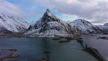 Fredvang viga voladiza puente, coche y volandstind montaña en invierno. flakstadoya, lofoten islas, paisaje de Noruega. aéreo vista. zumbido moscas oblicuo y hacia arriba video