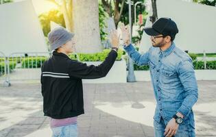 Side view of people greeting each other and shaking hands on the street. Two teenage friends shaking hands outdoors. Concept of two friends greeting each other with a handshake on the street photo