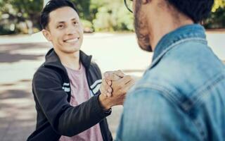 dos Adolescente amigos sacudida manos a cada otro al aire libre. dos personas sacudida manos en el calle. concepto de dos amigos saludo cada otro con apretón de manos en el calle foto