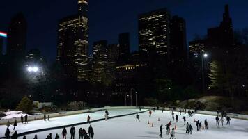 nuevo York ciudad, Estados Unidos - enero 22, 2021 personas vistiendo mascaras patinaje sobre hielo en Wollman pista en central parque en el noche durante coronavirus pandemia. Manhattan paisaje urbano video
