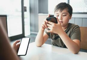 Young boy sitting with parent using mobile phone,Man hand holding smart phone ordering food in restaurant,Kid playing game or texting messages on cell phone to friends.Technology and Lifestyle concept photo