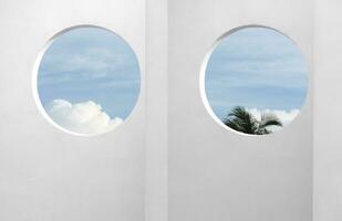 Architecture minimal exterior white wall cement surface texture,Concrete house with open window against blue sky and clouds, Modern building geometry with summer sky and coconut palm leaves photo