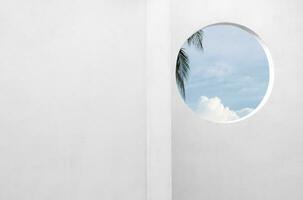 Architecture minimal exterior white wall cement surface texture,Concrete house with open window against blue sky and clouds, Modern building geometry with summer sky and coconut palm leaves photo
