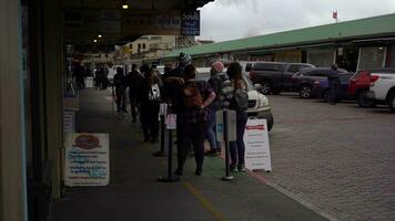 SEATTLE, USA - FEBRUARY 4, 2021 People Wearing Masks are Lined Up on Sidewalk and Practice Social Distancing Waiting to Enter Cafe During Covid-19 Pandemic. Pike Place video