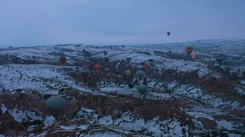 cappadoce, dinde - avril dix, 2021 air chaud des ballons dans neigeux la cappadoce dans hiver Matin. Turquie. aérien voir. drone est en orbite. video