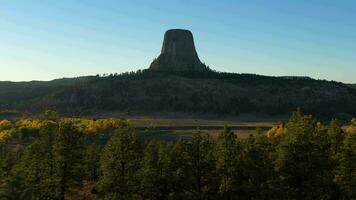 Teufel Turm Butte beim Sonnenuntergang im Herbst. Gauner Bezirk. Wyoming, USA. Antenne Sicht. Drohne fliegt rückwärts beim niedrig Niveau video