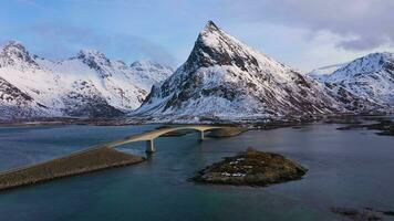 Fredvang mensola ponte, auto e volandstind montagna nel inverno a tramonto. Flakstadoya, lofoten isole, paesaggio di Norvegia. aereo Visualizza. fuco mosche indietro e verso il basso video