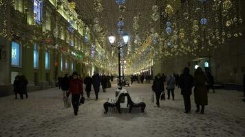 Moskou, Rusland - december 25, 2020 verlichte nikolskaja voetganger straat. wandelen mensen in winter avond. Kerstmis vakantie. Moskou, Rusland. video
