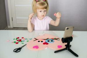 A blogger girl makes a felt craft for Valentine's Day in the shape of a heart. The concept of children's creativity and handmade. photo