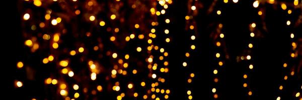 Blurry garland lights on a dark background. Festive Christmas and New Year background. Soft focus photo