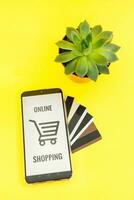Smartphone with the inscription-online shopping close-up. Online shopping, online banking, online payment. Payment with plastic cards. Flat Ley on a yellow background. photo