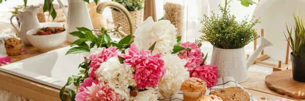 The kitchen countertop is decorated with peonies. The interior is decorated with spring flowers photo