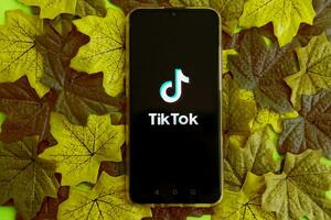 ver, Rusia - septiembre 19, 2020 Tik Tok aplicación en tu teléfono inteligente pantalla en un antecedentes de arce hojas. Tik Tok es un popular vídeo compartiendo social red foto