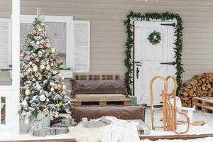 The porch of a country house decorated for Christmas and New Year holidays. Christmas tree on the porch of the house in winter. photo