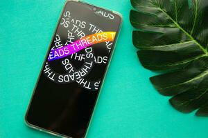 Tver, Russia - July 15, 2023, threads logo on the smartphone screen, on a green background. The threads icon. The logo of the current application. Threads social network. photo