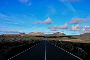 an empty road in the middle of a desert with mountains in the background photo