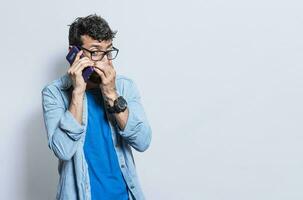 Person secretly talking on the phone. Young man secretly talking on the phone isolated, A guy secretly talking on the phone photo