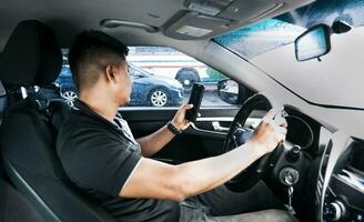 Distracted driver using the cell phone while driving, Man using his phone while driving, Person holding the cell phone and with the other hand the steering wheel, Concept of irresponsible driving photo