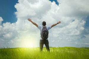 backpacker man in the field spreading his hands, concept of successful man spreading his hands photo
