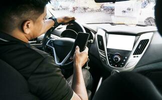 Person holding the cell phone and with the other hand the steering wheel, Distracted driver using the cell phone while driving, Man using his phone while driving, Concept of irresponsible driving photo