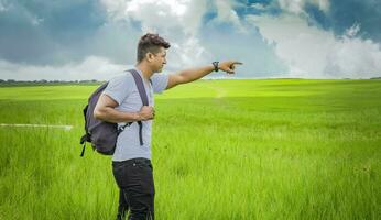 aventurero hombre en el campo, hombre con mochila en el campo mirando foto