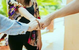 Close up of three friends bumping fists, Concept of friends fist bumping outdoors. Front view of three friends bumping fists in the street. Concept of union and commitment of friends. photo