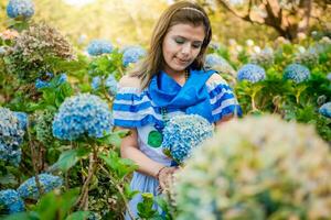 Portrait of girl in traditional Central American folk costume holding flowers in a nursery. Beautiful Nicaraguan woman in national folk costume holding flowers in a nursery photo