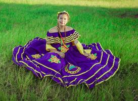 joven nicaragüense mujer en tradicional gente disfraz sentado en el césped en el campo, retrato de nicaragüense mujer en gente disfraz sentado en el césped foto