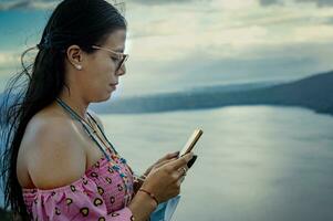 Latin woman checking her cell phone, pretty girl in glasses checking her cell phone photo