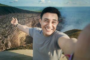 Tourist taking a selfie at a viewpoint. Handsome tourist taking a selfie on vacation. Adventurous man taking a selfie at a viewpoint. Close up of person taking an adventure selfie photo