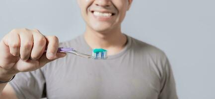 Young man showing toothbrush with toothpaste isolated, guy holding brush with toothpaste on white background, Person showing a toothbrush with toothpaste photo