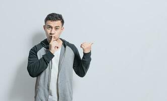 Person pointing to the side giving an offer isolated, people with finger on lip pointing to the side, Handsome man with finger on lip pointing to the side on isolated background photo