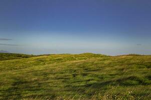 picture of a hill with clouds and blue sky, picture of a hill with blue sky in the background photo