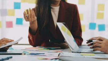 två kreativ företag människor möte och planera använda sig av posta den anteckningar klibbig notera på skrivbord till dela med sig aning, analys data Diagram och Graf med lagarbete strategi brainstorming i kontor. video