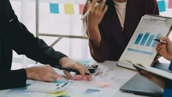 Two creative business people meeting and planning use post it notes sticky note on desk to share idea, Analysis data chart and graph with teamwork strategy brainstorming in office. video