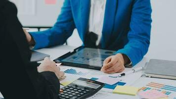 två kreativ företag människor möte och planera använda sig av posta den anteckningar klibbig notera på skrivbord till dela med sig aning, analys data Diagram och Graf med lagarbete strategi brainstorming i kontor. video