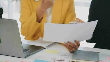 Two creative business people meeting and planning use post it notes sticky note on desk to share idea, Analysis data chart and graph with teamwork strategy brainstorming in office. video