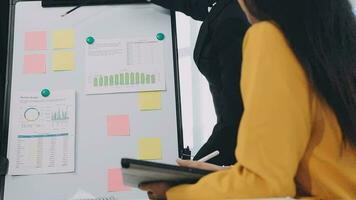Two creative business people meeting and planning use post it notes sticky note on desk to share idea, Analysis data chart and graph with teamwork strategy brainstorming in office. video