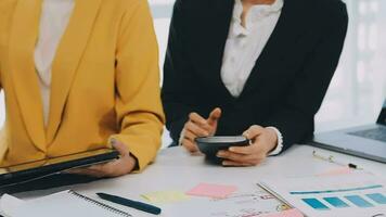 två kreativ företag människor möte och planera använda sig av posta den anteckningar klibbig notera på skrivbord till dela med sig aning, analys data Diagram och Graf med lagarbete strategi brainstorming i kontor. video