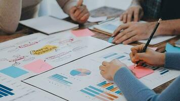 Two creative business people meeting and planning use post it notes sticky note on desk to share idea, Analysis data chart and graph with teamwork strategy brainstorming in office. video
